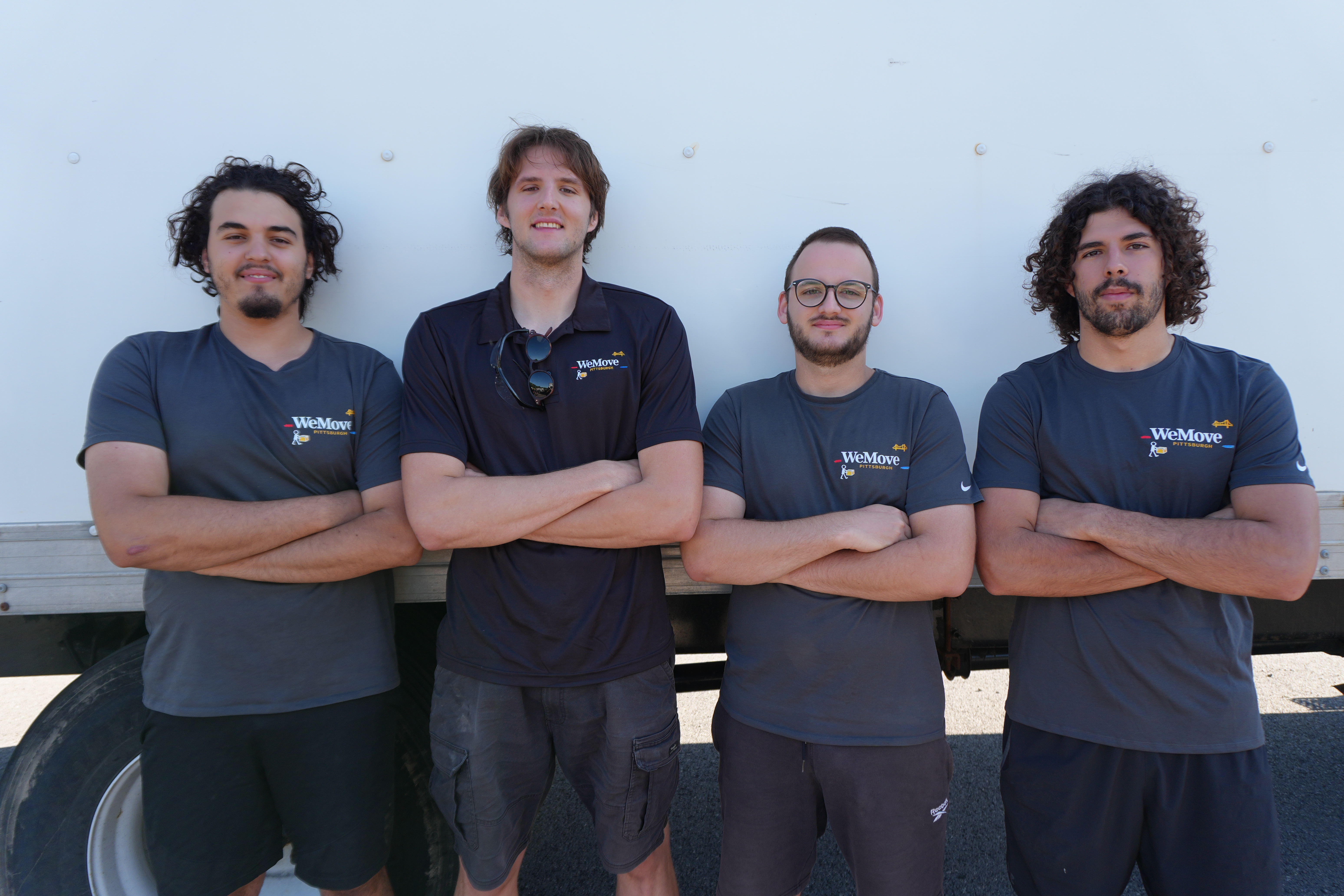 Four WeMove Pittsburgh crew members with arms crossed in front of the moving truck